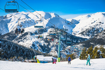 People riding up on a ski chair lift and skiing and snowboarding down on the ski slope. Winter...