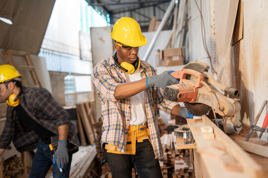 African american male carpenter hacksaw cutting door frames handmade workshop back yard having coworkers picking wood at furniture factory