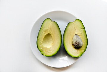 Green avocado fruit cut into slices on a white background. Avocado on a white plate. Avocado slices and halves