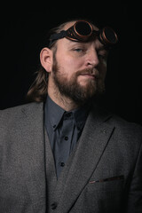 charismatic man in a classic suit and steampunk goggles on a black background stylish Portrait