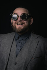 charismatic man in a classic suit and steampunk goggles on a black background stylish Portrait