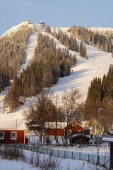 Beautiful little wooden mountain houses, huts with a ski slope surrounded by forest on a sunny winter day. Skiing resort in Sweden, Funasdalen covered in snow