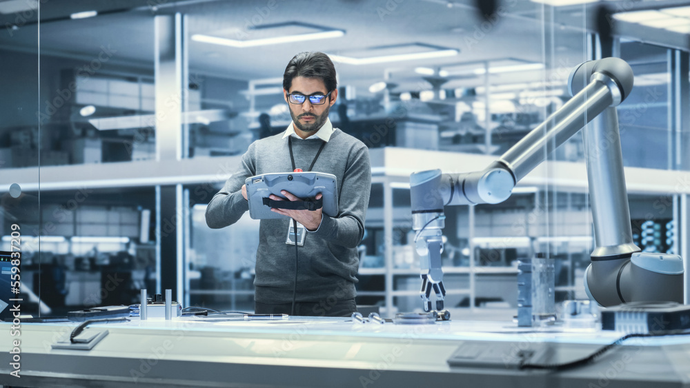 Poster Robotics Engineer Researching and Developing a Technological Robot Arm Project, Standing with Tablet Computer in Scientific Technology Lab. Young Male Working on an AI Robotic Arm.