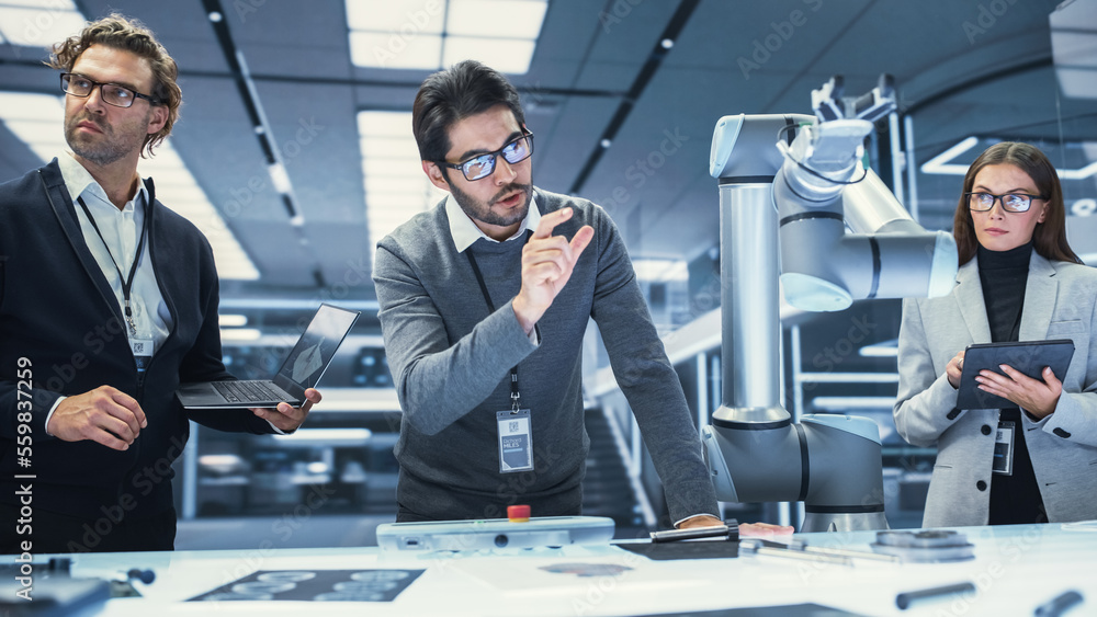 Poster Team Leader Working with Robotics Engineers on a Robot Arm Project, Discussing the Project in Scientific Technology Lab. Young Team Researching and Developing an AI Robotic Arm in Industrial Facility.