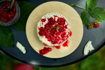 Cake with rice crisp bread and raspberry jam on a black background, outdoor garden fresh bush,...