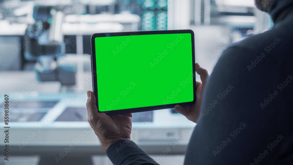 Fototapete Robotics Engineer Using a Tablet Computer with Green Screen Mock Up Display Screen Running Augmented Reality. Robotic Arm Holding a Microchip. Automation Startup Research and Development Office.