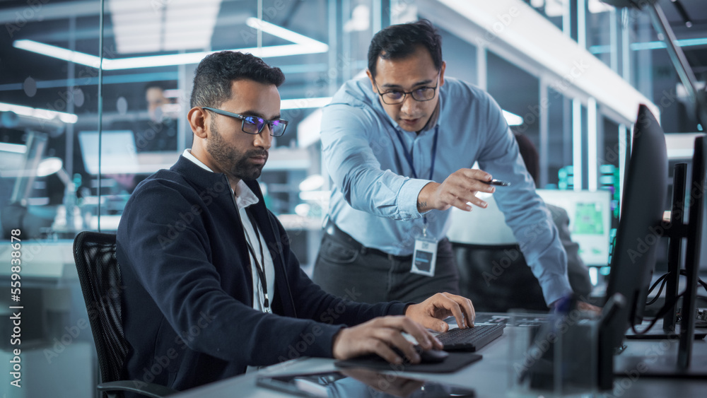 Leinwandbilder Male Project Supervisor Talks to an Industry 4 Engineer Who Works on Desktop Computer in Robotics Startup Industrial Office. Software Developer Discussing Work Related Tasks During a Meeting.