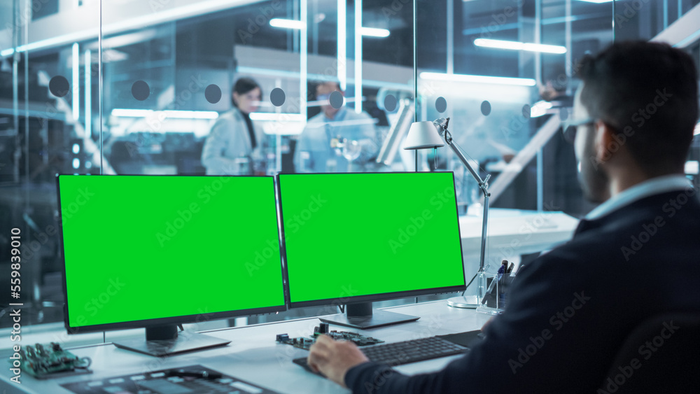 Aufkleber Industrial Engineer Working on a Desktop Computer with Two Green Screen Chromakey Display Screens in a Modern Technological Research and Development Center. Over the Shoulder Shot.