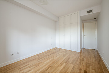 Room with a built-in wardrobe with three doors with a mezzanine with a trunk and air conditioning through ducts installed in the false ceiling, studs on the walls, walls, doors and white skirting