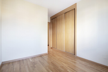 Room with a built-in wardrobe with three sliding oak doors with matching skirting boards and floors...
