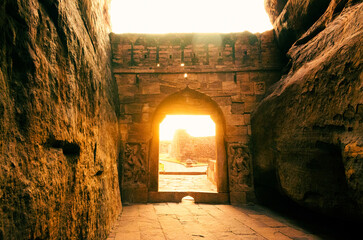 Beautiful sunlight coming out of Badami fort ,gateway to lower Shivalaya temple during sunset. - obrazy, fototapety, plakaty