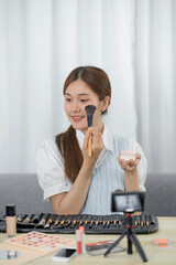 Beauty blogger. Cheerful asian vlogger is showing cosmetics products giving advices for her beauty blog