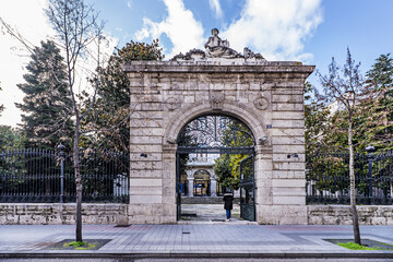 Obraz premium Monumental stone door of a metal wrought iron fence at the entrance to a farm with a small palace inside