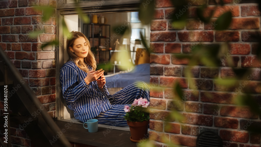 Aufkleber A Beautiful Woman in Comfortable Pyjamas Using Smartphone While Sitting on a Windowsill on a Warm Afternoon. White Female Using an Online Dating App and Matching with Different People