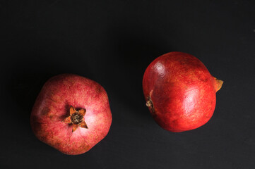 Fototapeta na wymiar Two whole red pomegranate fruits on a black background top view in natural light
