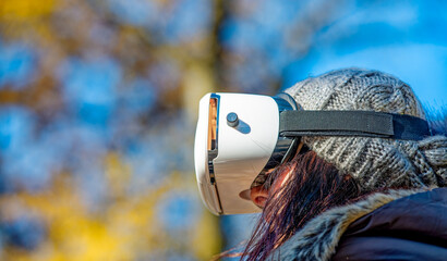 Happy woman wearing a virtual reality visor exploring the city park