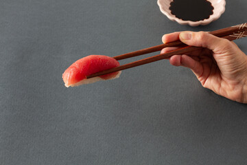 Crop person with sashimi in chopsticks