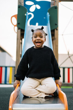Cheerful black girl playing on slide