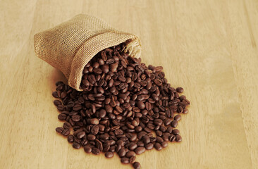 Sack of coffee beans on wooden background