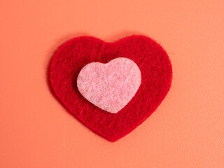 Heart of different colors on a pink background.