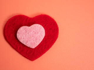 Heart of different colors on a pink background.