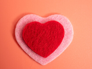 Heart of different colors on a pink background.