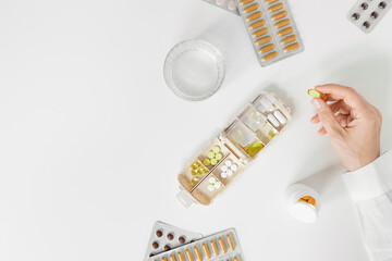 Top view medical tablets, capsules, nutrition supplements in women hands and glass of water on...