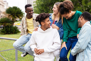 Happy multiethnic group of young friends having fun together outdoor. Friendship and community concept with multiracial teenager people hanging out in city street