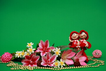Obraz na płótnie Canvas Spring bouquet of orchid flowers. On a beautiful gentle green background. Souvenir red figurine of a fairy girl. Macro. Postcard with floral wallpaper. Romantic artistic image, place for tex 