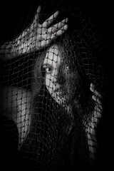 face of girl behing a net on a dark background with a back light - art picture