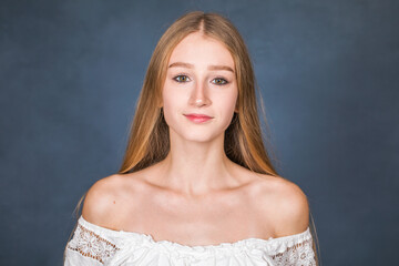 Portrait of a young beautiful blonde girl in white dress