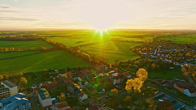 Aerial view of Oschersleben  at sunset. Drone flight over the village with green fields .  Oschersleben is a town in the Börde district, in Saxony-Anhalt, Germany