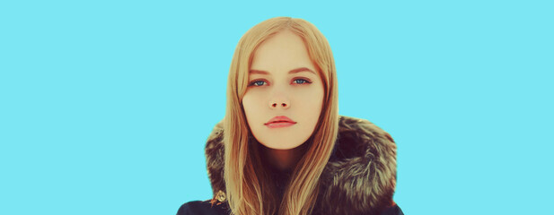 Winter portrait of beautiful young blonde woman on blue background