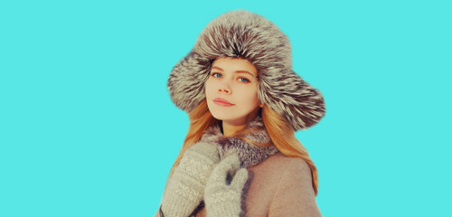 Portrait of beautiful young blonde woman in winter hat on blue background