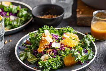 Red cabbage, kale, orange, parmesan and walnuts salad. Dark backround. 