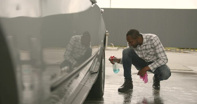 Black Man Cleaning The Rims Of His Car At Car Wash