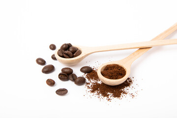 Ground coffee and coffee beans in wooden spoons isolated on white background.