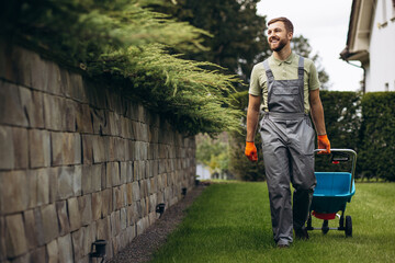Gardner with cart sprinkling fertilizer