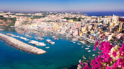 view of Procida island colorful town with small harbour from above with flowers, Italy, web banner format