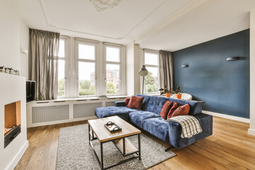 a living room with blue walls and hardwood flooring, including a large sofa in the center of the...
