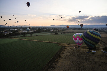 Landscape of sunrise with hot air balloons rising over fields and ancient teotihuacán ruins...