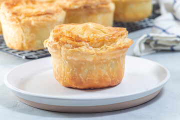 Small beef pot pies on plate and cooling rack, horizontal