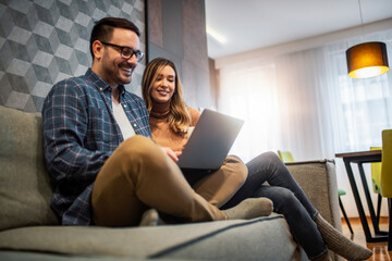 Couple using laptop in living room at home