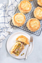 Sliced beef pot pie on plate, pies on cooling rack, vertical, top view