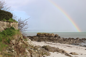 Natural rainbow in the sky at the beach starting from the sea. Rainbow after the rain in the ocean.