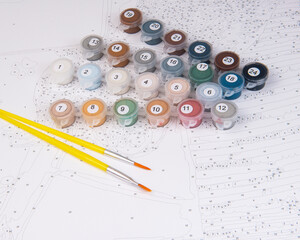 A set of colorful gouache paints, brushes and canvas with numbers is ready for drawing education....