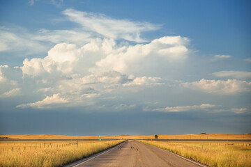 Highway cutting between pasture land under a srormy cloudy sky in a South Dakota landscape