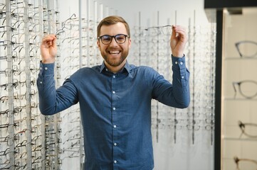 Naklejka premium male client chooing new eyeglasses frame for his new eyeglasses in optical store