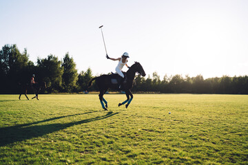 Active female Polo player riding horse on green field