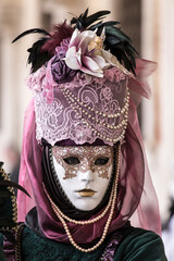 ritratto verticale di una persona in maschera al carnevale di venezia, cappello con piume e perle pendenti